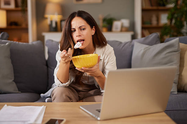istock Woman eating snack while working from home on laptop 2246156457