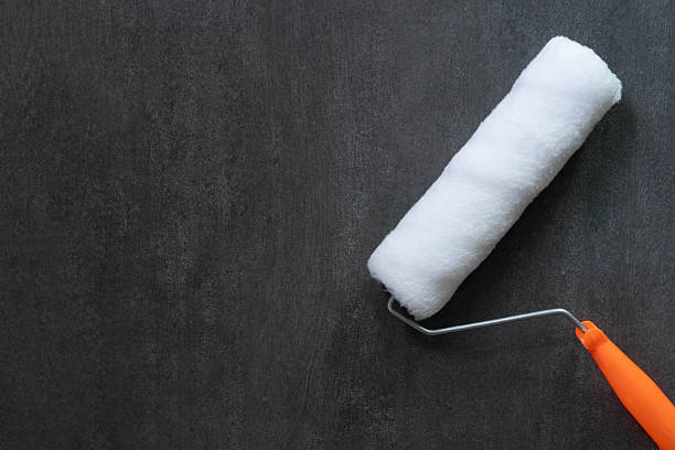 close up brush painting roller white on the black table background, diy and repair house concept
