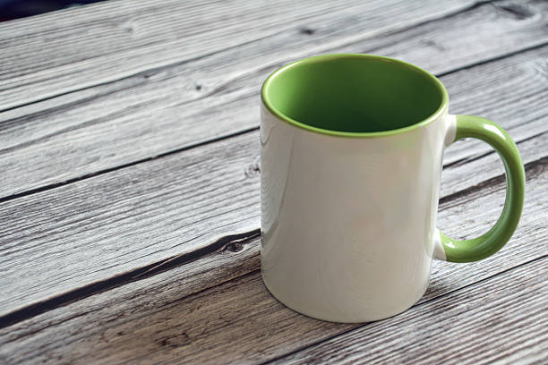 Empty cup on a wooden table. White mug with green handle. Cup and table