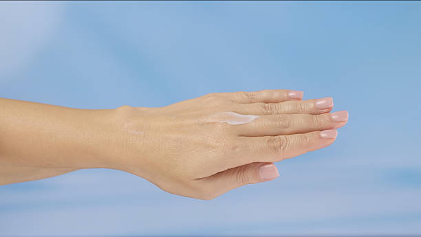 Hand with Moisturizing Cream Against Blue Background
