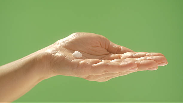 istock Hand Holding Cream Against Simple Green Background 2246164699