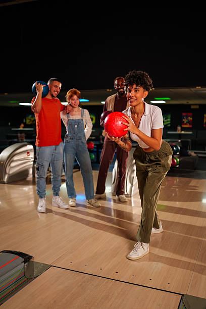 istock Young woman bowling while friends cheer enthusiastically, sharing laughter and excitement during a lively night out at the alley 2246166840