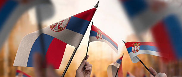 istock Serbia flags in their hands on a blurred urban background 2246166854