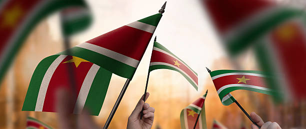 istock Suriname flags in their hands on a blurred urban background 2246167870