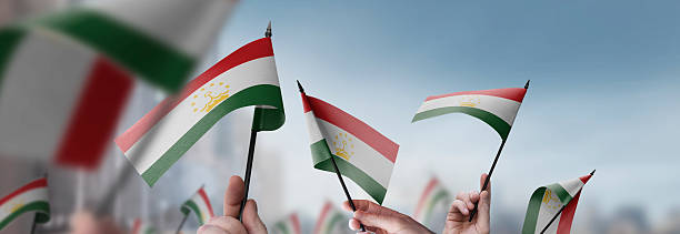 istock Tajikistan flags in their hands on a blurred urban background 2246169325