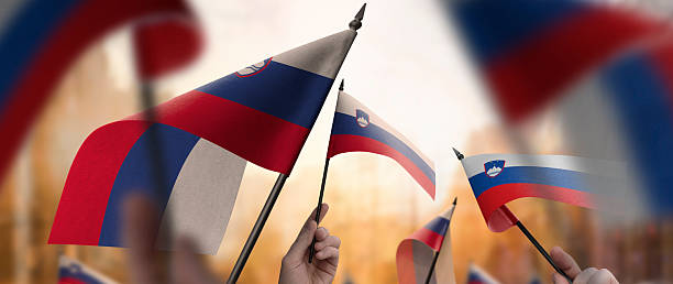 istock Slovenia flags in their hands on a blurred urban background 2246169515