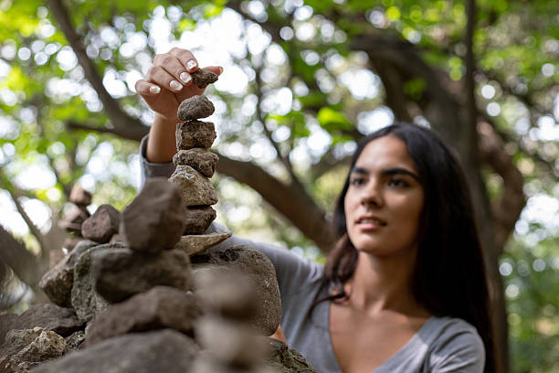Beautiful young hispanic woman stacking stones on a forest trail
