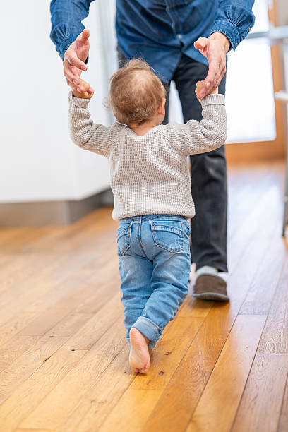 istock Joyful Caucasian Baby Taking First Steps with Father's Support in Cozy Home 2246171962