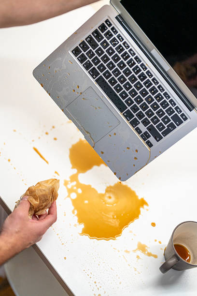 istock Concerned Person Quickly Cleaning Coffee Spill From Laptop on White Desk 2246172009