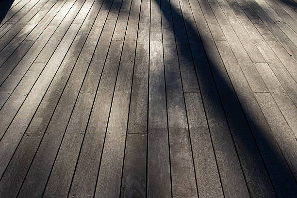 istock A wooden deck in perspective filling the entire frame, with shadows falling across. 2246172124