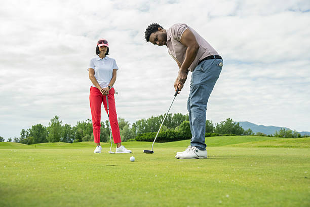 istock Focused Young Hispanic Male Putting on Golf Course as Mature Hispanic Female Observes 2246172995