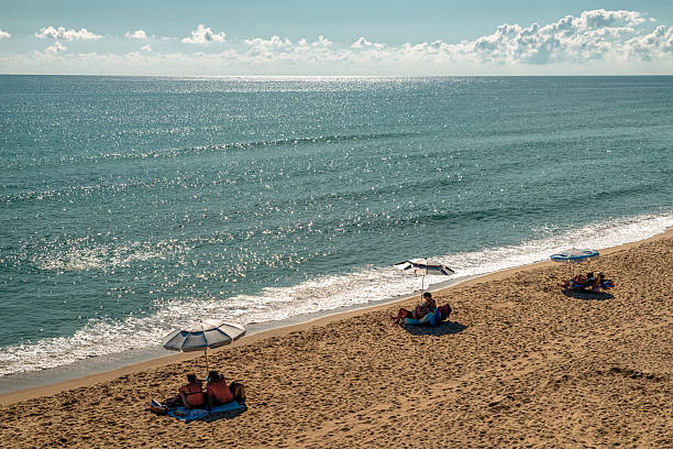 Byala, Bulgaria - September 21, 2025: People relaxing under umbrellas on sandy beach by the Black Sea during bright summer day. Warm travel scene of seaside tourism.