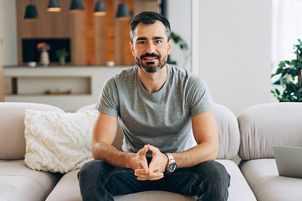 istock Smiling confident man relaxing on sofa at home 2246173520