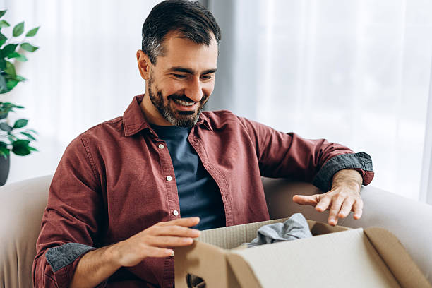 istock Man unboxing delivery box finding online shopping gift 2246173629