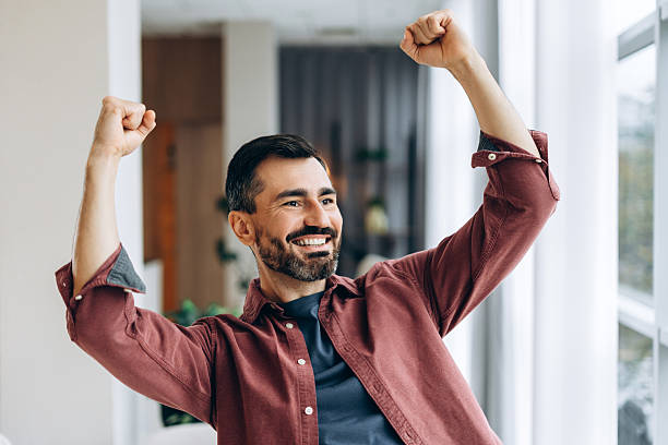istock Happy man celebrating triumph with hands raised 2246173633