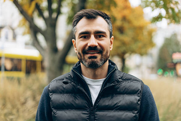 istock Smiling man wearing puffer vest in autumn park 2246174452