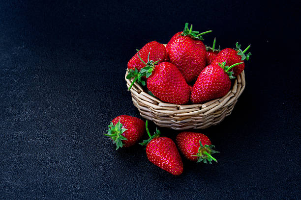 istock Fresh strawberries arranged in a woven basket on a dark background showcasing their bright red color and green stems 2246175090