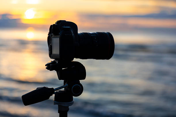 istock Camera on tripod by the sea in evening light. Camera at sunset. 2246178553