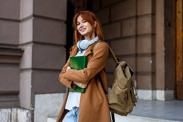 istock Young student smiling outdoors holding book on campus 2246180066