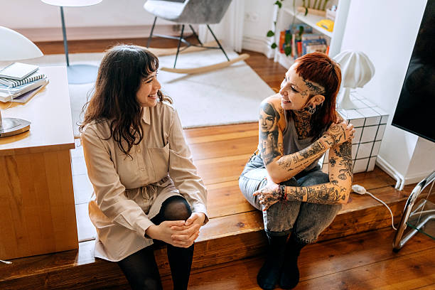 istock Two cheerful female friends talking while sitting on the floor at home 2246180577