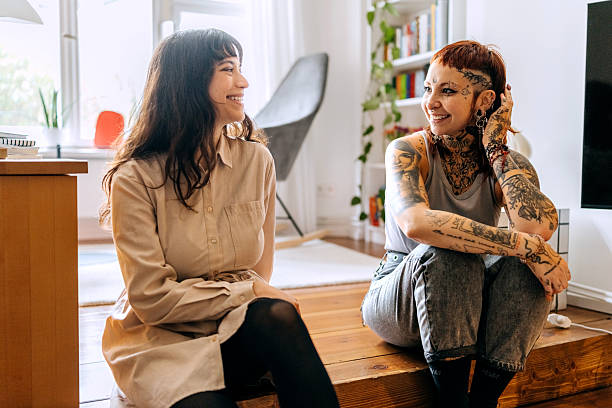istock Two cheerful female friends talking while sitting on the floor at home 2246181148