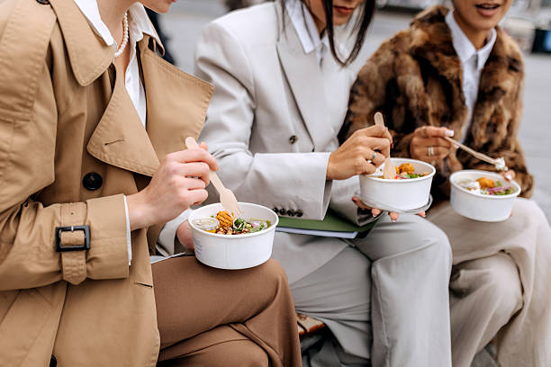 istock Three female coworkers having lunch outdoors on a city bench 2246181853