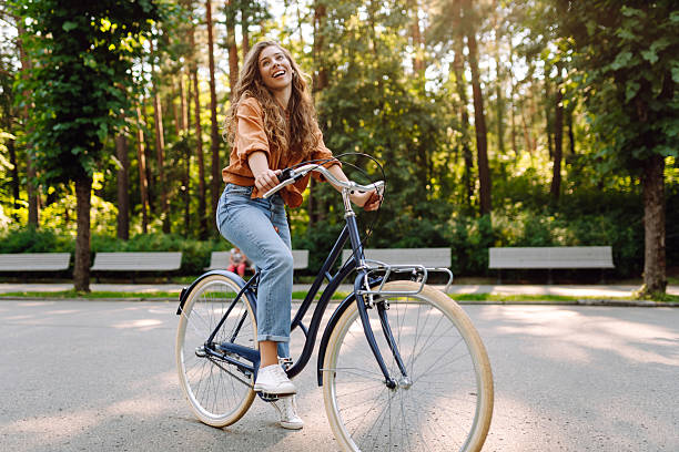 istock A cheerful woman rides a bicycle along a path in a green park. 2246181893