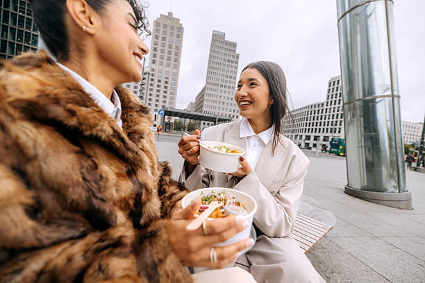 istock Two businesswomen having lunch outdoors on city bench 2246181920