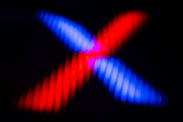 Abstract, dark background featuring two crossing zig-zag beams of contrasting red and blue light, forming an X shape.