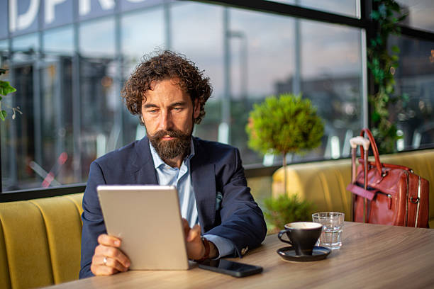 istock Businessman working remotely using tablet at a coffee shop 2246185122