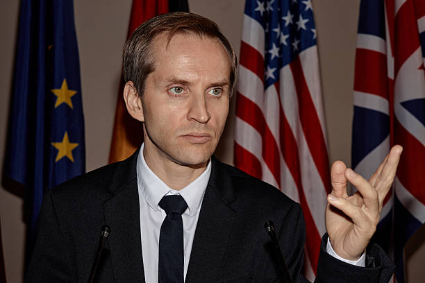 istock Caucasian Middle Aged Man Speaking at Press Conference with International Flags 2246185567