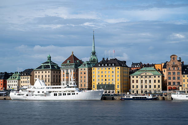 Serene Stockholm skyline at sunset, with historic architecture, calm waterfront, and boats, viewed from Skeppsholmen. Tranquil Nordic charm.