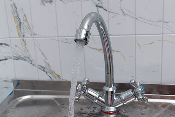 istock Flowing Water from Modern Faucet in Marble-Tiled Kitchen Sink Setting 2246188266