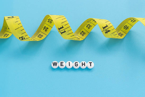 istock Yellow tape measure with text Weight on light blue background 2246193507