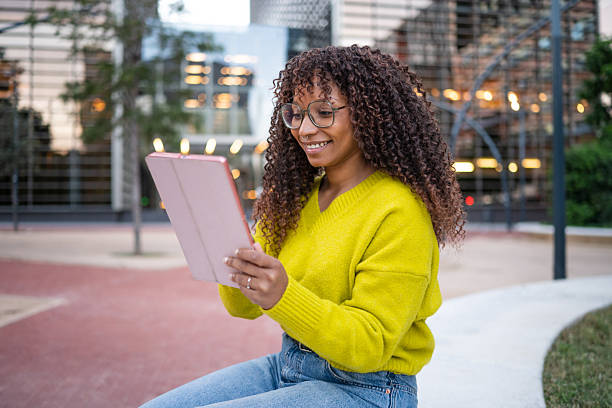 istock Smiling young woman using tablet in urban park 2246196931