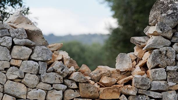 Close-up of an old dry stone wall with a broken section and natural background, representing tradition, craftsmanship and the passage of time in rural landscapes.