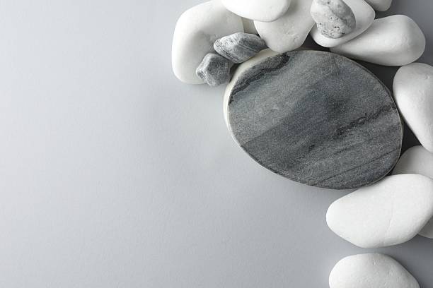 Presentation for product. Stone podium and pebbles on light grey background, top view. Space for text