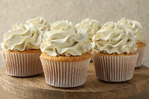 istock Tasty vanilla cupcakes with cream on table, closeup 2246201258