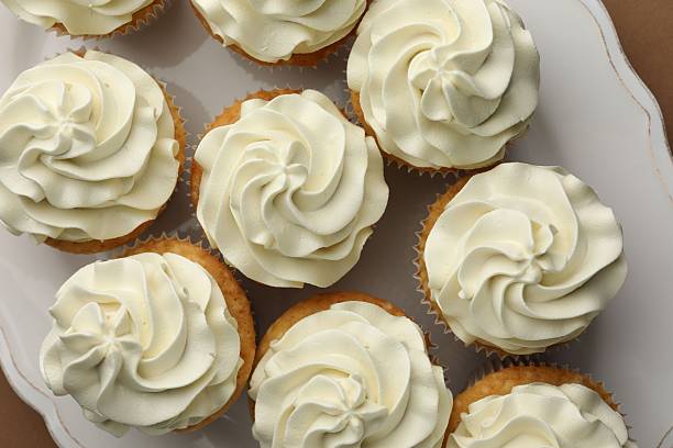 istock Tasty vanilla cupcakes with cream on table, flat lay 2246201379