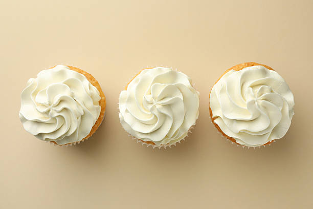 istock Tasty vanilla cupcakes with cream on beige background, top view 2246201680