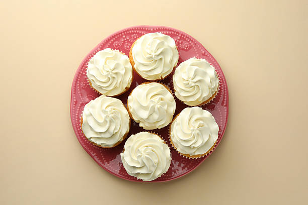 istock Tasty vanilla cupcakes with cream on beige background, top view 2246201692