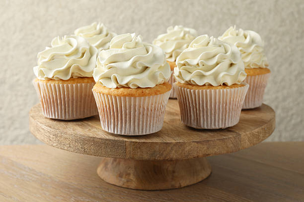 istock Tasty vanilla cupcakes with cream on wooden table 2246201724