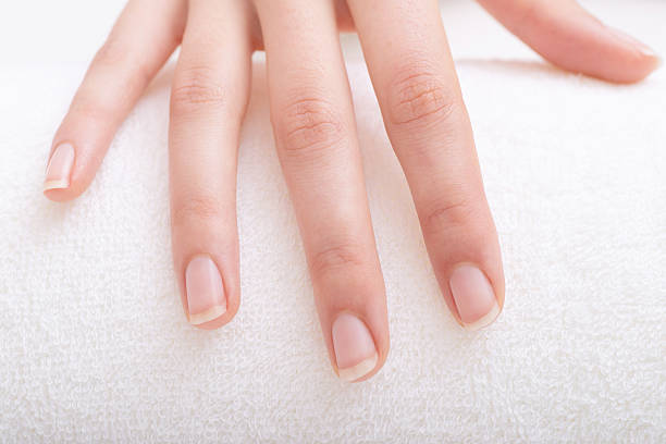 Manicured fingernails on the elegant female hand on the towel.