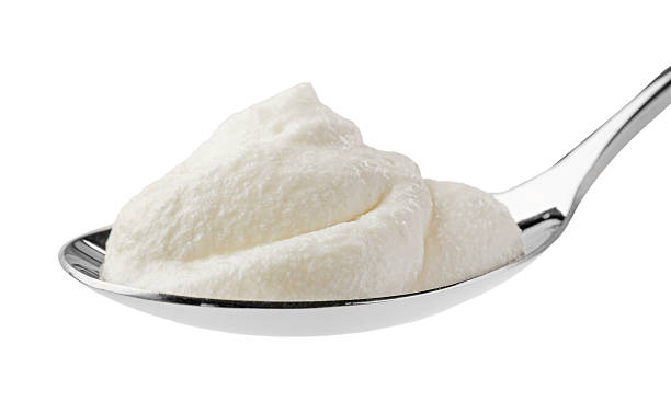 istock Silver spoon with sour cream isolated on white 2246210591
