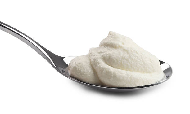 istock Silver spoon with sour cream isolated on white 2246210608