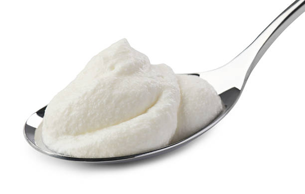 istock Silver spoon with sour cream isolated on white 2246210609