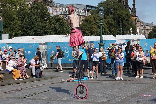 Edinburgh, Scotland - 18 August 2025: A juggler on a unicycle has attracted a small audience.
