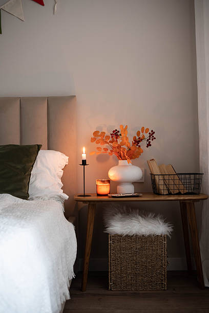 istock Cozy fall decor in a light and bright bedroom, bed, white bed sheets, autumn branches in white vase, candles and books on wooden bench. 2246212581
