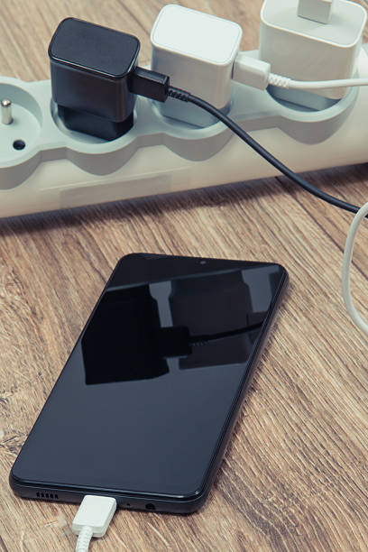 istock Black smartphone and chargers connected to electrical power strip. Various devices charging concept 2246214745