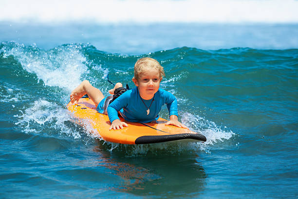 istock Happy young surfer boy with surfboard have fun on beach, riding on small ocean waves. Summer adventures, active families, parents and kids lifestyle, sports activities on school holiday with kids 2246222973